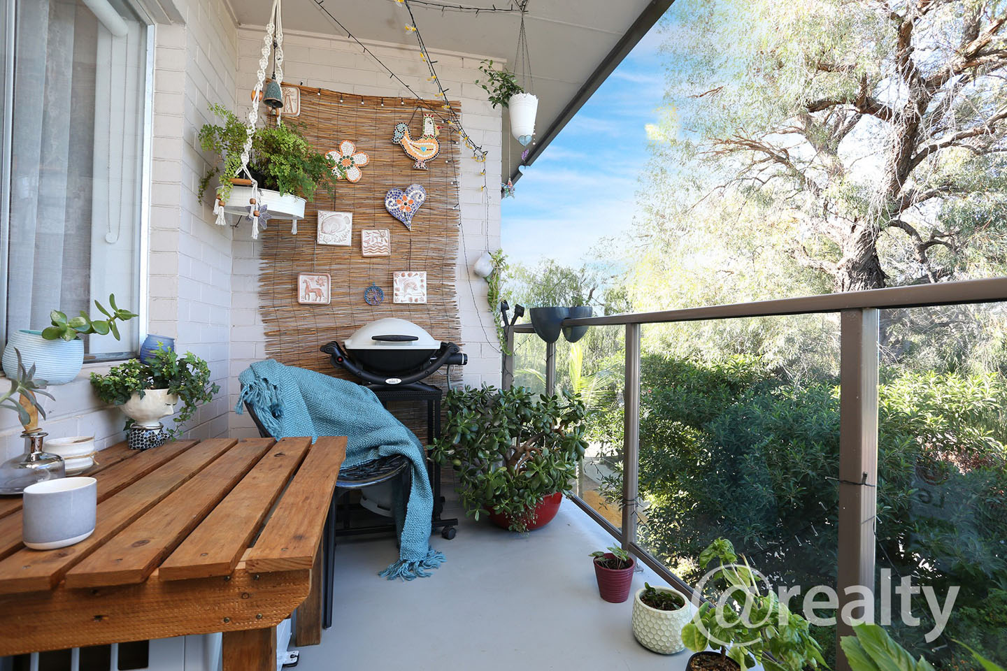 Cozy balcony with plants and wall decor.