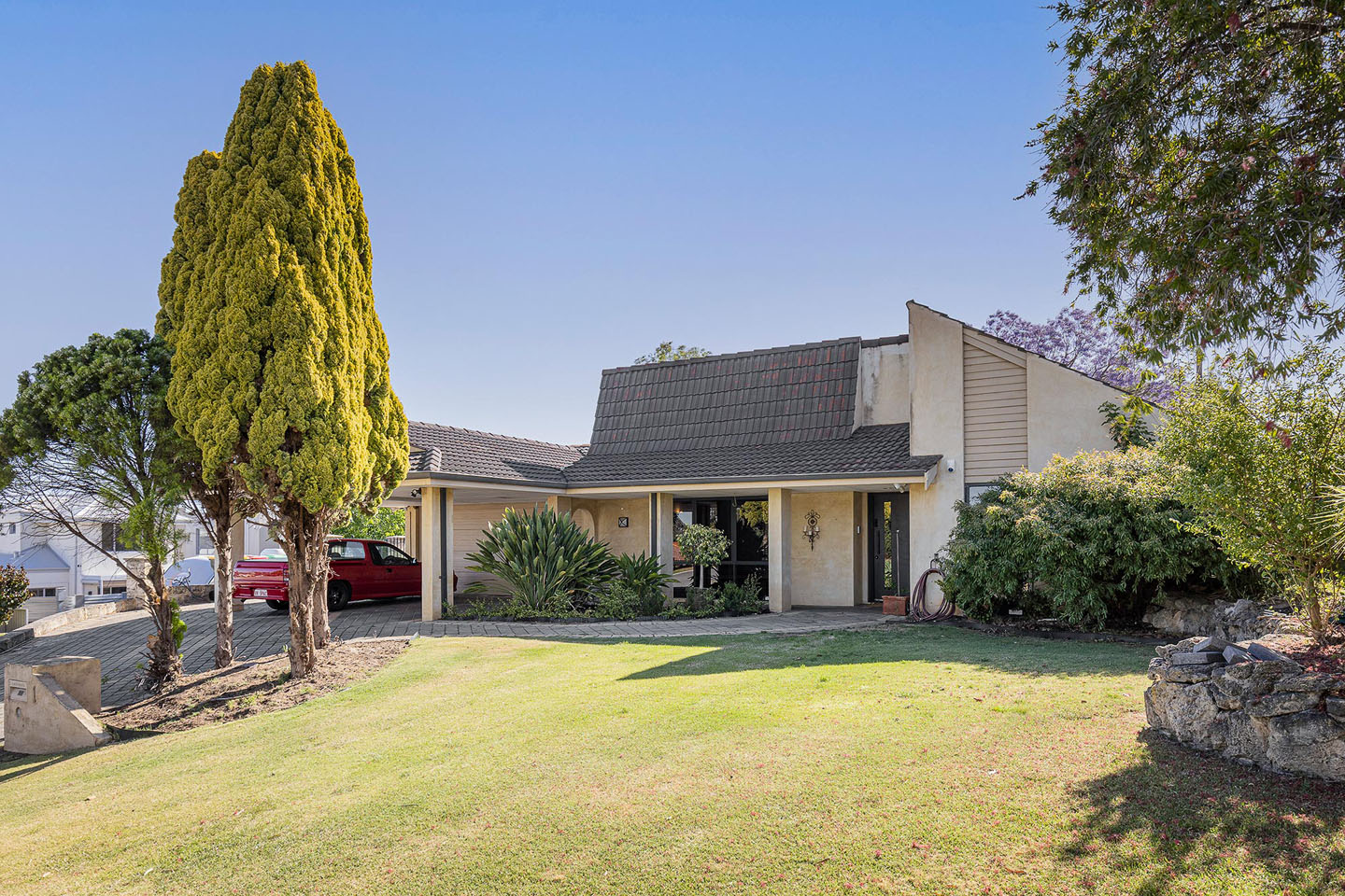 Charming house with landscaped front yard and trees.