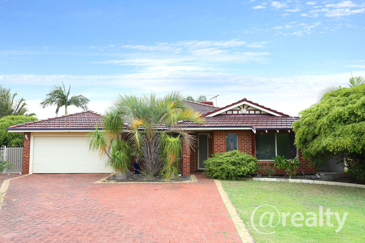 Single-story brick house with palm trees and garage.
