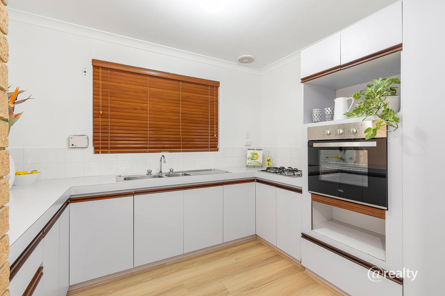 Modern white kitchen with wooden blinds and oven.