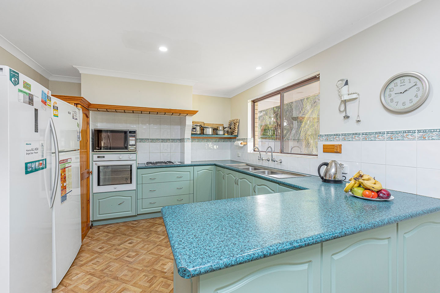 Cozy kitchen with teal cabinets and appliances.