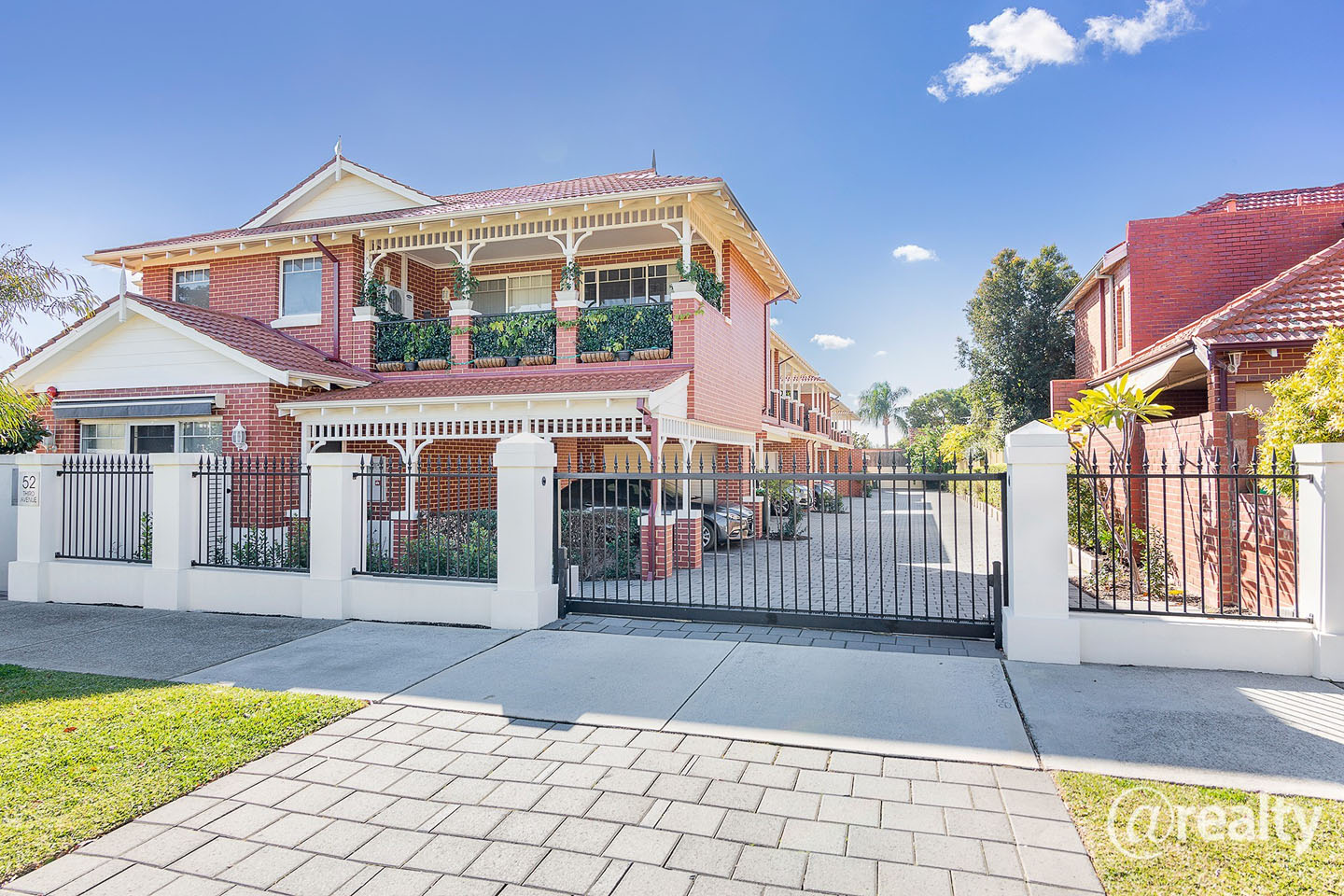 Charming brick apartment building with greenery and gate.